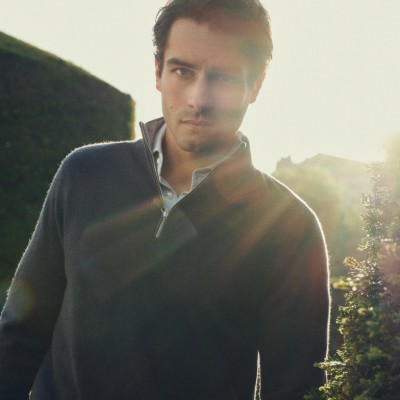 Man wearing a N.Peal sweater outdoors with sunlight filtering through